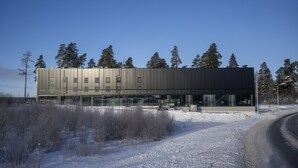 A modern building with a flat roof and large windows, surrounded by snow and trees. - Playhotel (Mjolby)