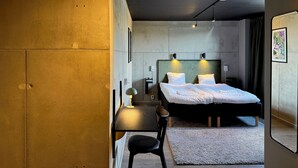 A modern hotel room with a large bed, a desk, and a chair. - Playhotel (Mjolby)