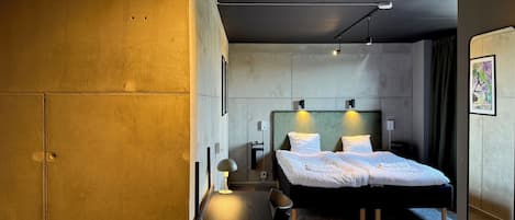 A modern hotel room with a large bed, a desk, and a chair.