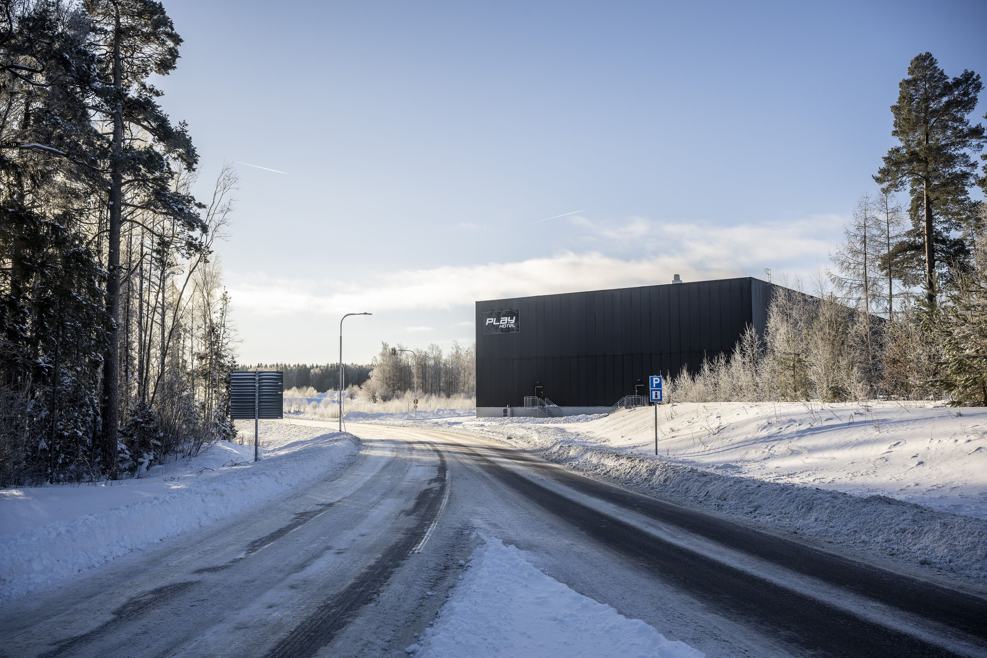 En snötäckt väg leder fram till en stor industribyggnad med en skylt som visar ordet ”LEK”.
