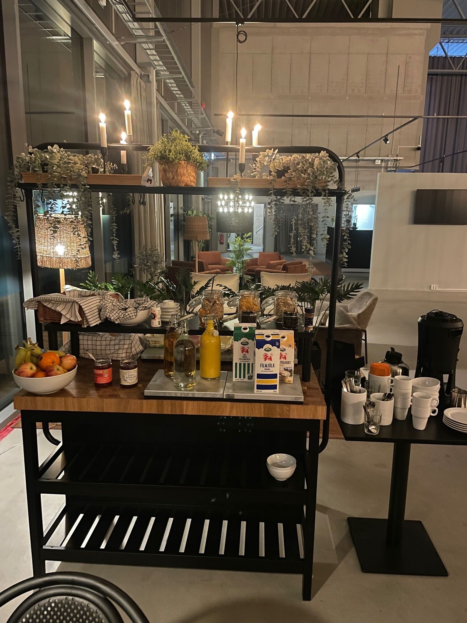 A food cart with various food items and condiments, surrounded by seating and a hanging light fixture.