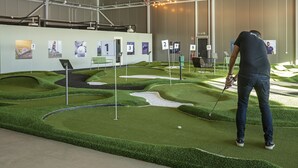 A miniature golf course with numbered holes and a player in a dark shirt and jeans. - Playhotel (Mjolby)