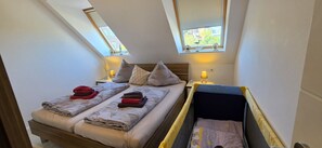 A room with a bed, a bedside table, a lamp, and a window.