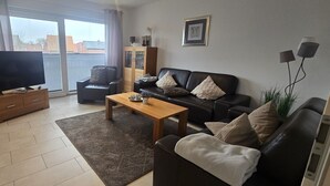 A living room with a TV, a sofa, a coffee table, and a cabinet. - Strandkrabbe: Your vacation by the sea! (Borkum)