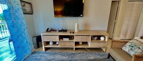Ein Wohnzimmer mit Flachbildfernseher an der Wand, einer Holz-Unterhaltungseinrichtung mit Regalen, einer Couch und einem Couchtisch.