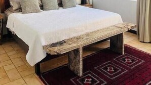 A bedroom with a bed, a wooden bench, a nightstand, a lamp, and a large window with curtains. - Hermosa palms beach house (Playa Hermosa)