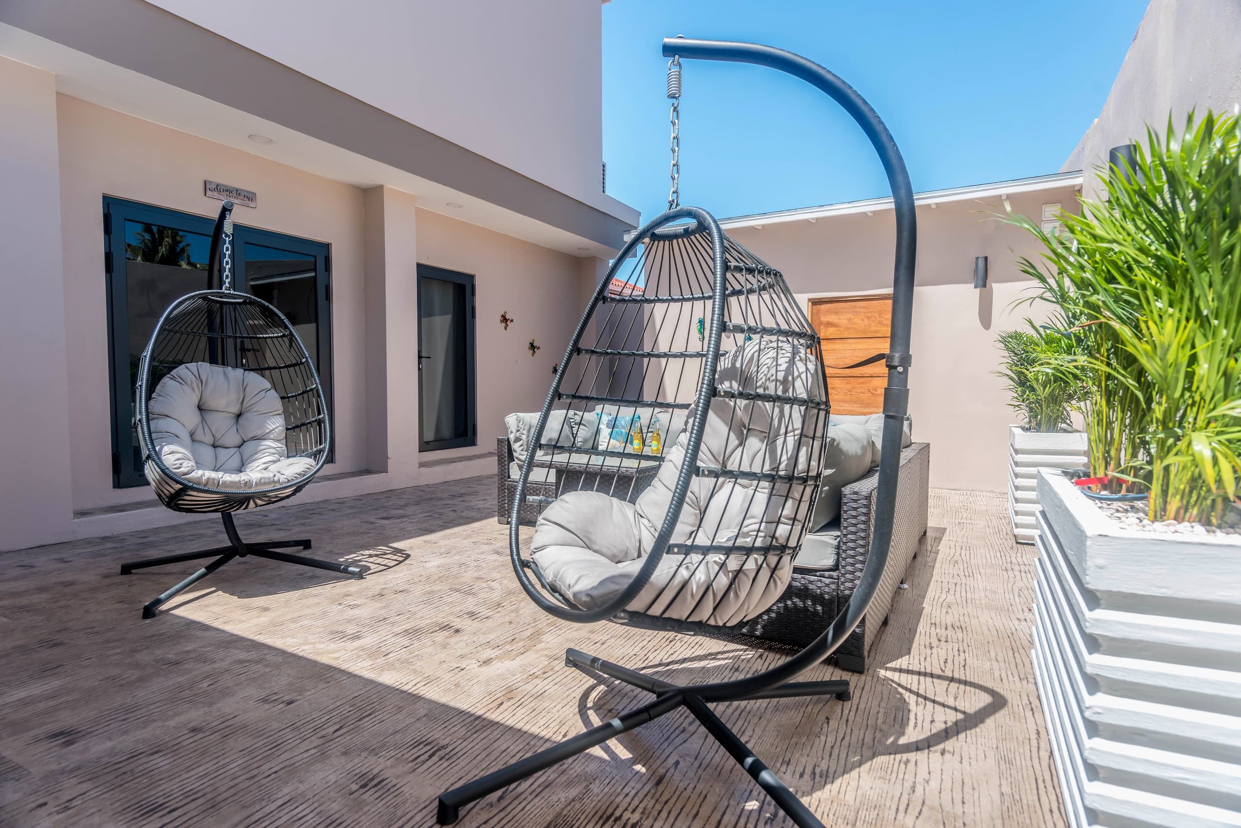 Two hanging chairs with cushions, a wooden floor, and a clear sky.