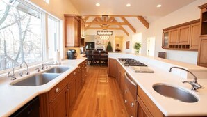 A spacious kitchen with wooden cabinets, a large island with a sink, and a view of the outdoors. - Secluded Spa-cious Retreat -Beds for 8. Plus 3 foldaways extra (Minneapolis)