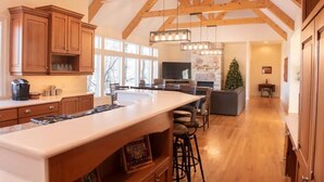 A spacious kitchen with a large island, wooden beams, and a stone fireplace. - Secluded Spa-cious Retreat -Beds for 8. Plus 3 foldaways extra (Minneapolis)