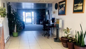 Un hall de hotel con mostrador de recepción, sillas, plantas en macetas y obras de arte en las paredes.