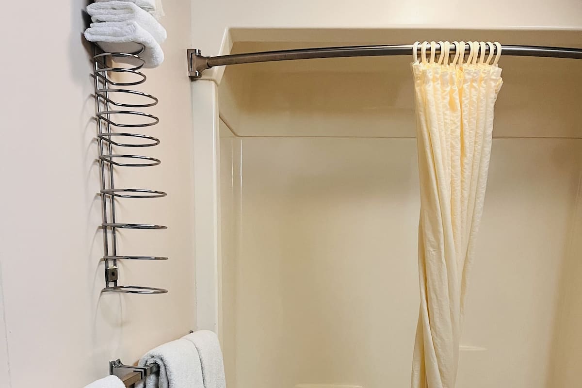 A bathroom with a bathtub, a toilet, and a towel rack with multiple towels.