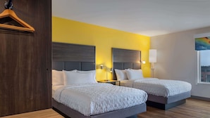 A hotel room with two beds, a wooden bench, and a view of the city. - Tru By Hilton Ankeny (Ankeny)