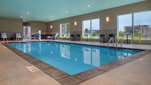 An indoor swimming pool with clear blue water, surrounded by lounge chairs and tables. - Tru By Hilton Ankeny (Ankeny)