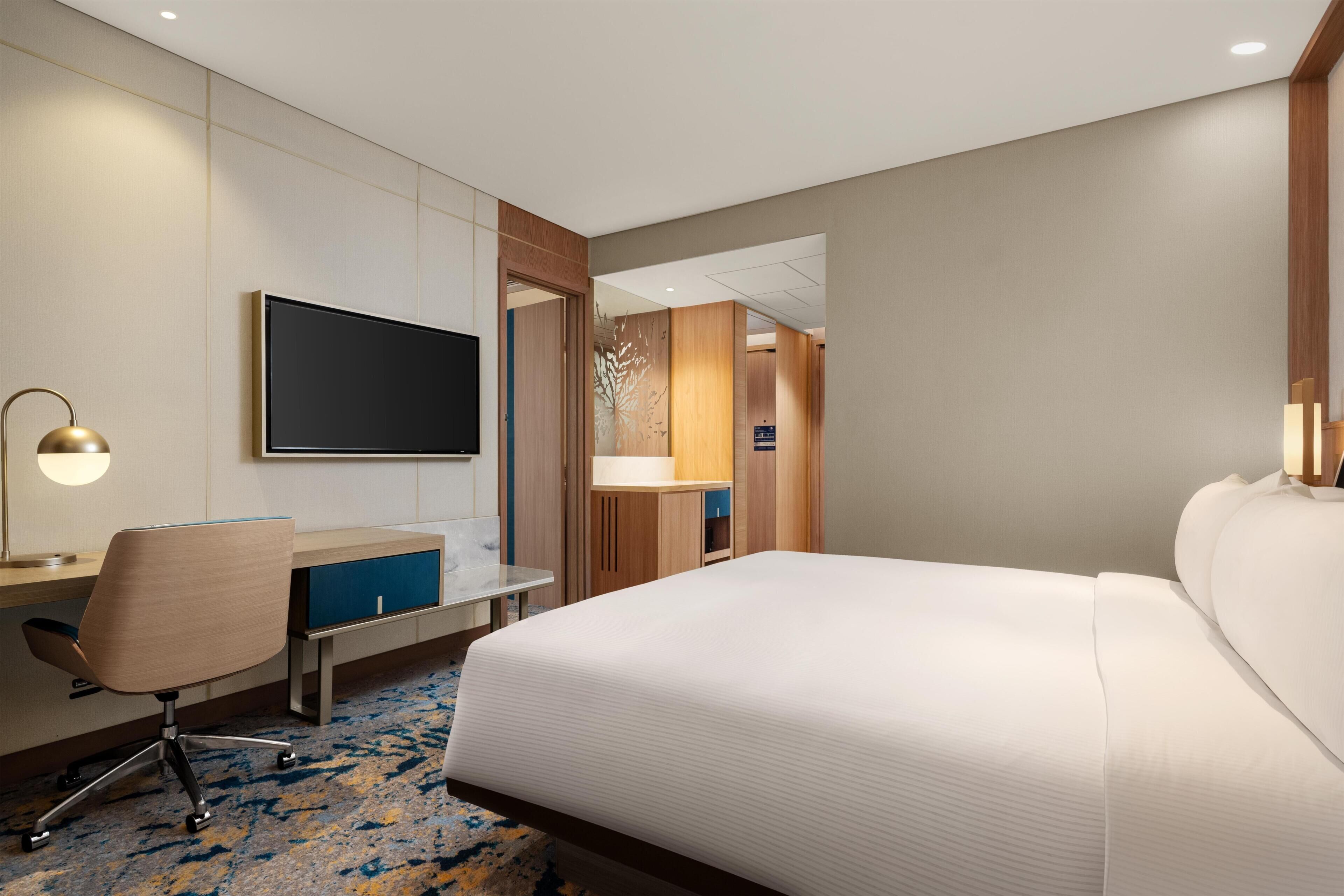 Une chambre d’hôtel équipée d’un lit, d’un bureau, d’une chaise et d’un téléviseur.