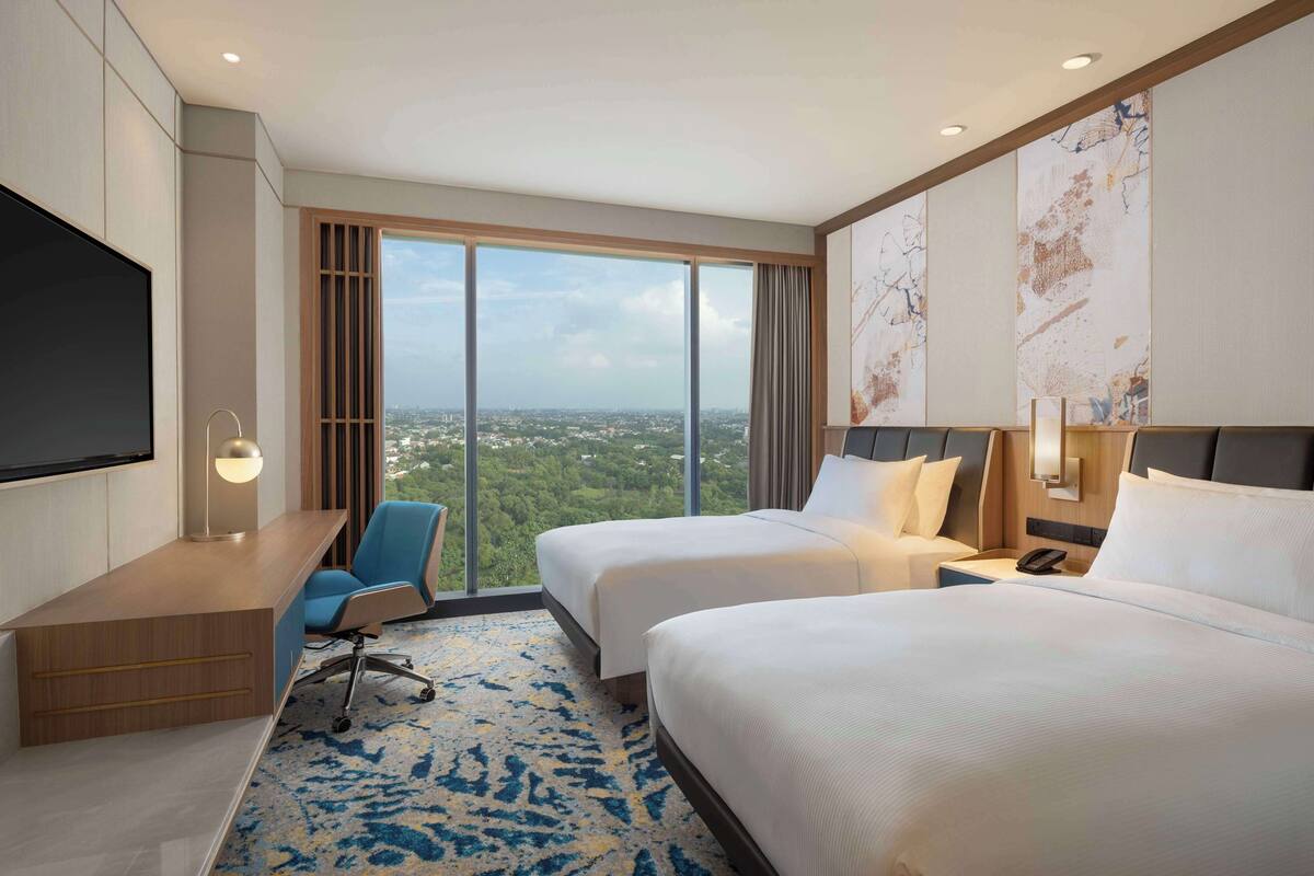 A hotel room with a large bed, a desk, a chair, and a TV.