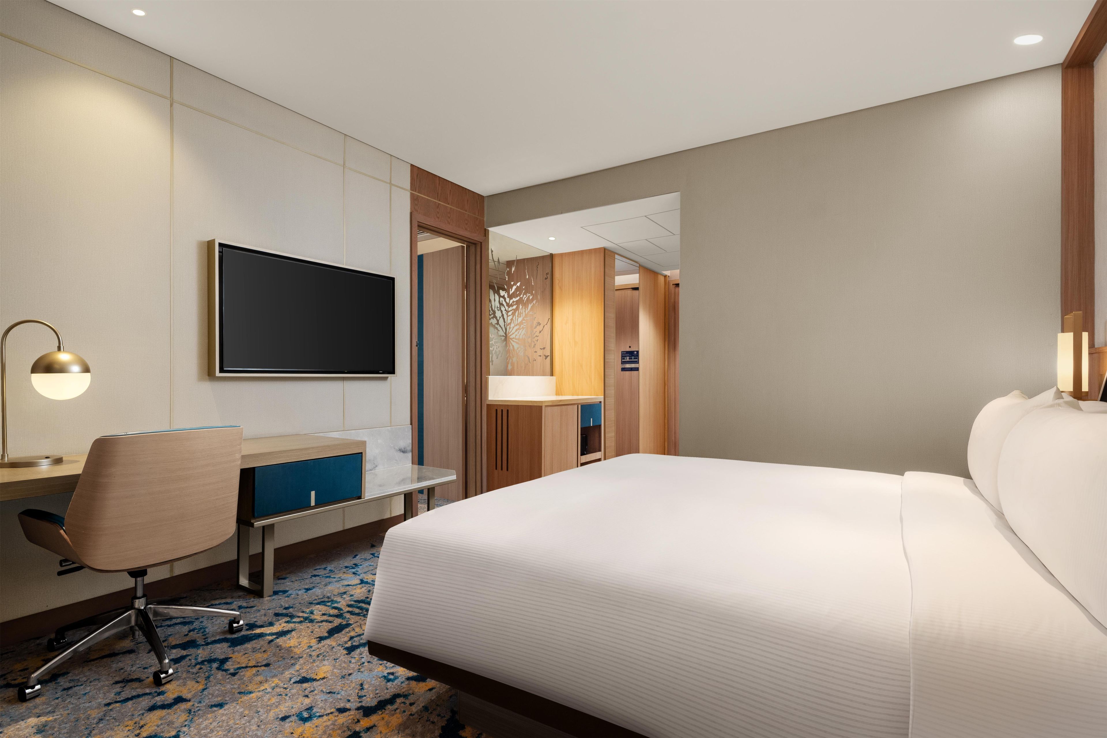 Une chambre d’hôtel équipée d’un lit, d’un bureau, d’une chaise et d’un téléviseur.