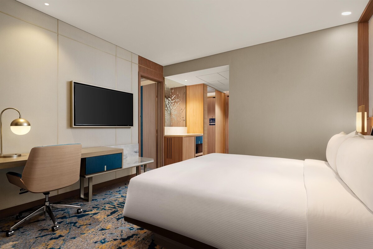 Una habitación de hotel con cama, escritorio, silla y televisión.