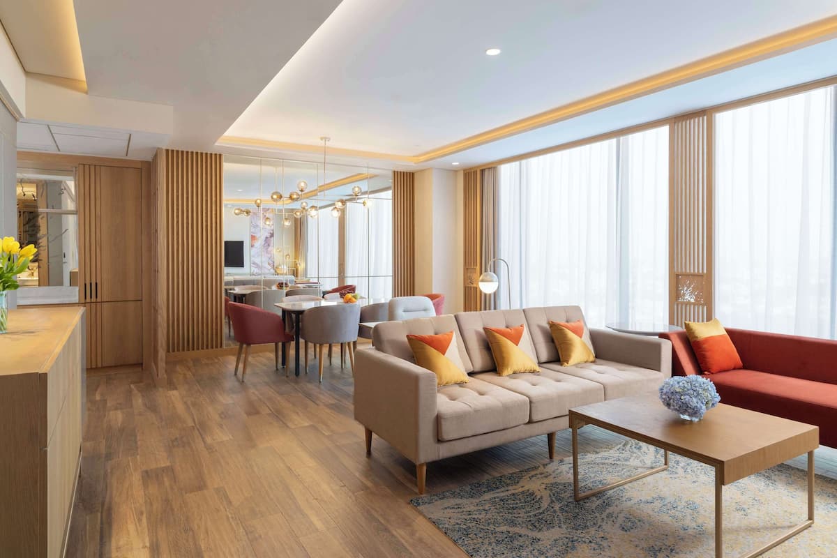 A modern living room with a sofa, coffee table, and a dining area with chairs and a table.