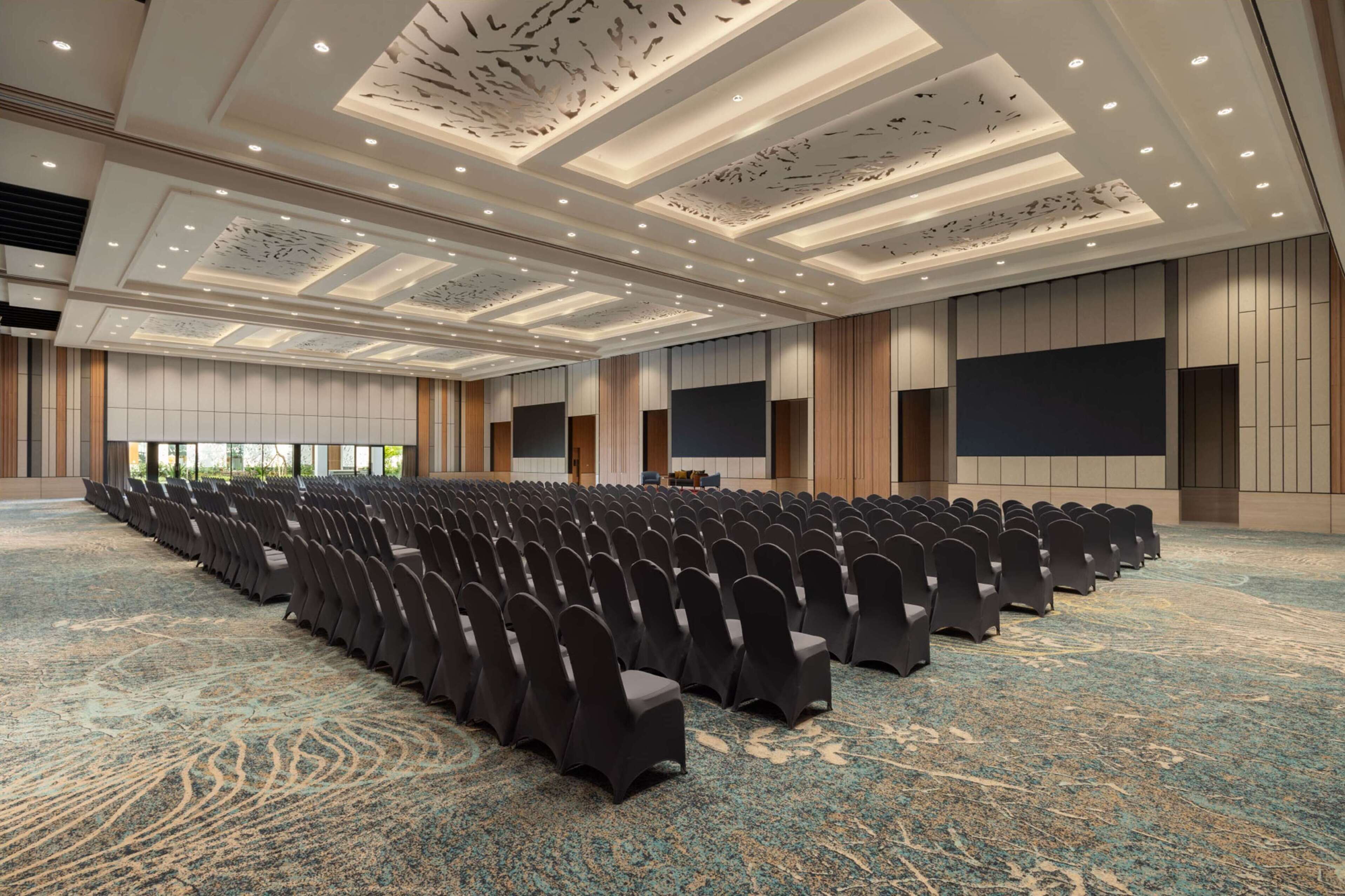 A large conference room with rows of chairs, a podium, and a large screen.