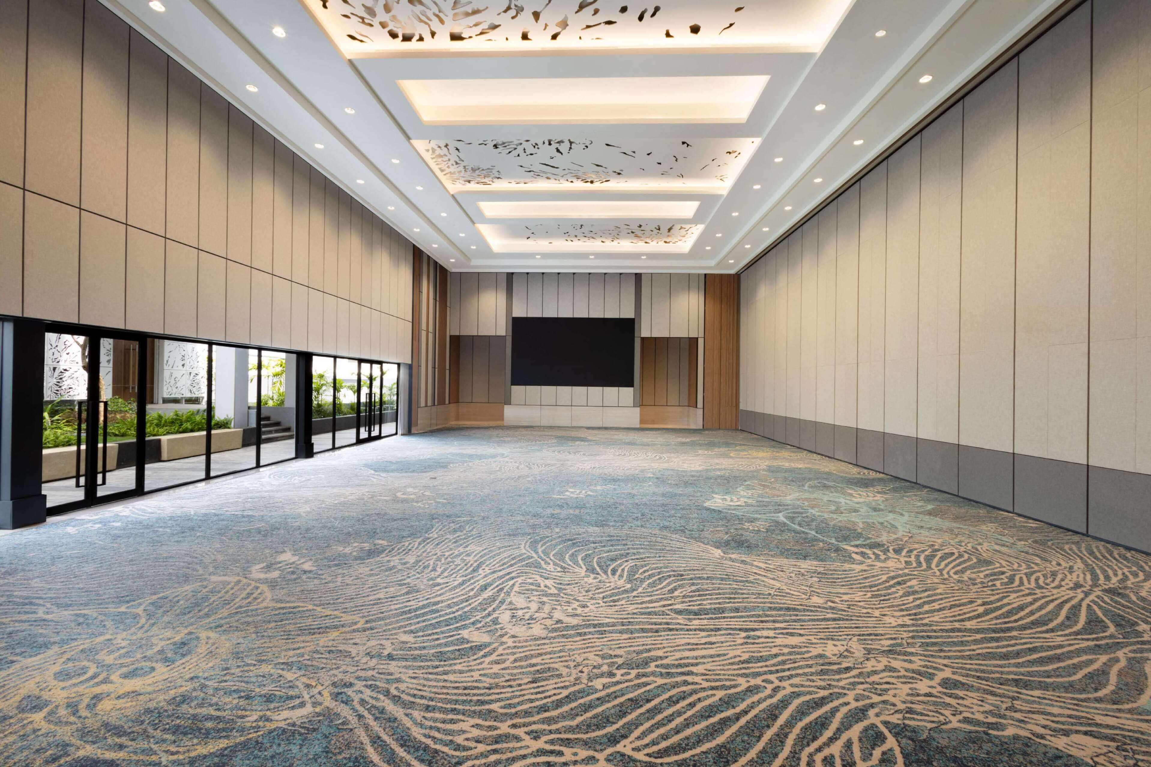 A spacious conference room with a large screen, recessed lighting, and a patterned carpet.