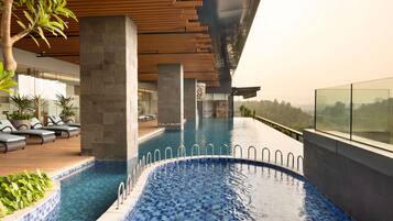 Una piscina interior moderna con agua azul cristalina, listones de techo de madera y vistas del paisaje circundante.