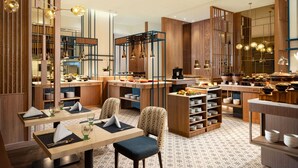Un interior de restaurante moderno con detalles de madera, iluminación colgante y mesas y sillas ordenadas.