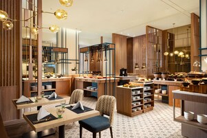 Ein modernes Restaurant mit Holzelementen, Pendelleuchten und ordentlich angeordneten Tischen und Stühlen.