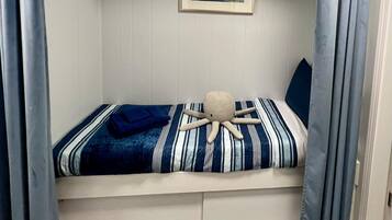 A bunk bed with a striped bedspread, a framed picture on the wall, and a plush octopus toy on the bed.