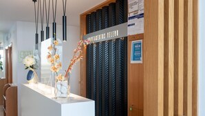 Una mesa de recepción con un letrero que dice "RECEPTION VELERO", un panel de pared de madera y una vitrina de vidrio con flores y piedras.