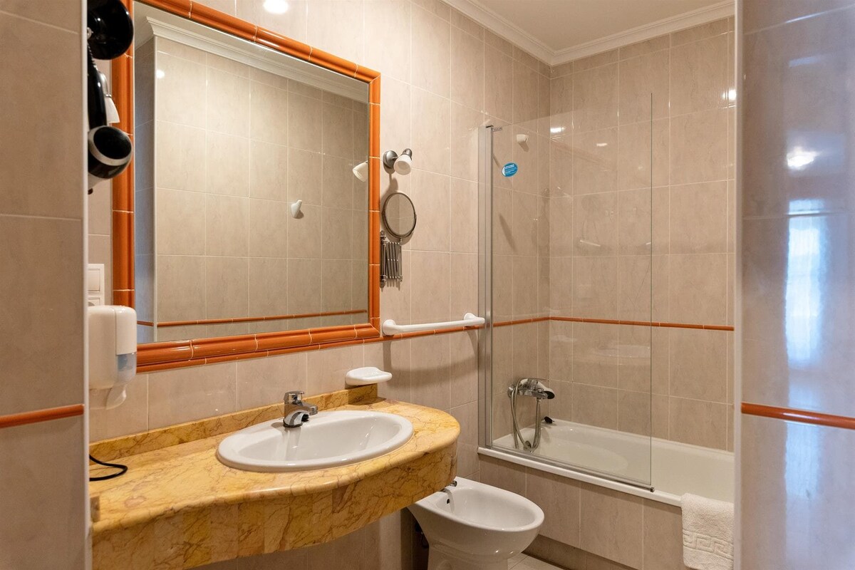 Een badkamer met een wastafel, spiegel, toilet en douchecabine.