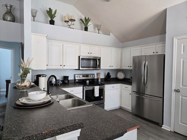 A modern kitchen with white cabinets, stainless steel appliances, and a granite countertop.