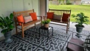 Un portico con due panche di legno, un pavimento decorato e piante in vaso.