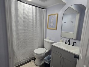 A bathroom with a toilet, sink, and shower curtain.