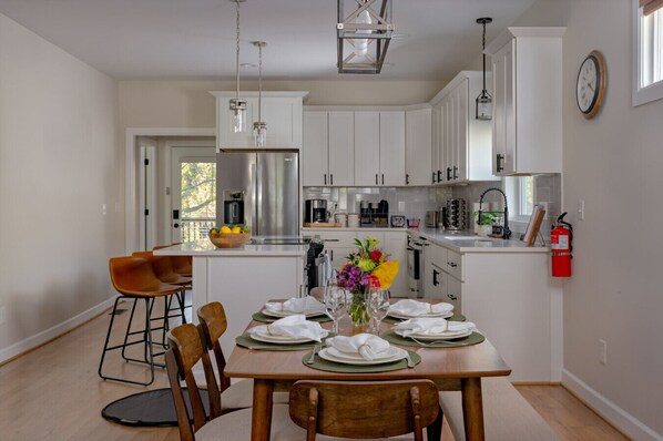 A modern kitchen with white cabinets, stainless steel appliances, and a dining area with a wooden table set for four.