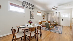 Een eethoek met een houten tafel voor vier personen, een plafondventilator en uitzicht op de woonkamer.