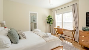 Een slaapkamer met een bed, bureau, stoel en plafondventilator.