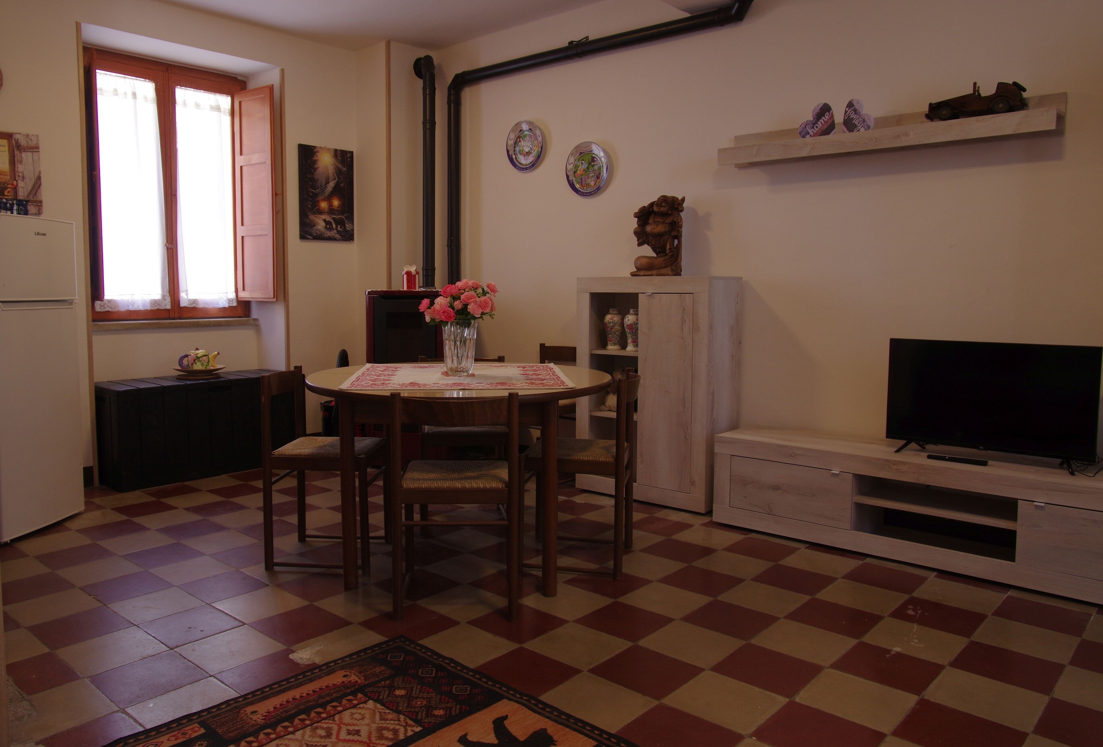 Une cuisine de taille réduite comprenant une table à manger, des chaises, un téléviseur et une fenêtre avec des rideaux.