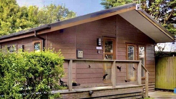 A small, single-story wooden cabin with a porch, a small deck, and a fenced yard. - Inviting 2-bed Lodge in Harrogate (Harrogate)