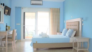 A bedroom with a bed, a desk, and a chair. There is a television on the wall and a window with curtains. - Villa Thomas Nakas (Parga)