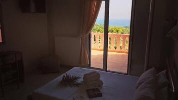 Habitación de hotel con cama, ventana con cortinas, radiador y vista a zonas verdes.