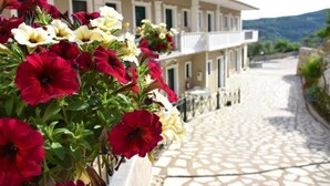A building with a stone-paved courtyard and a balcony with flowers. - Villa Thomas Nakas (Parga)