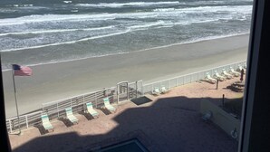 Blick auf einen Strand mit einer Flagge, Liegestühlen und einem Zaun.