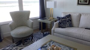 Ein Wohnzimmer mit Meerblick, ein Sessel, eine Couch, ein Couchtisch und eine Lampe.