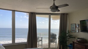 Ein Schlafzimmer mit einem großen Bett, einem Deckenventilator, einem Balkon mit Meerblick und einer Kommode mit Schubladen.