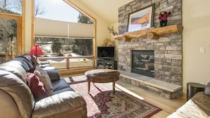 Una sala de estar acogedora con chimenea de piedra, un ventanal grande y un sofá cómodo.