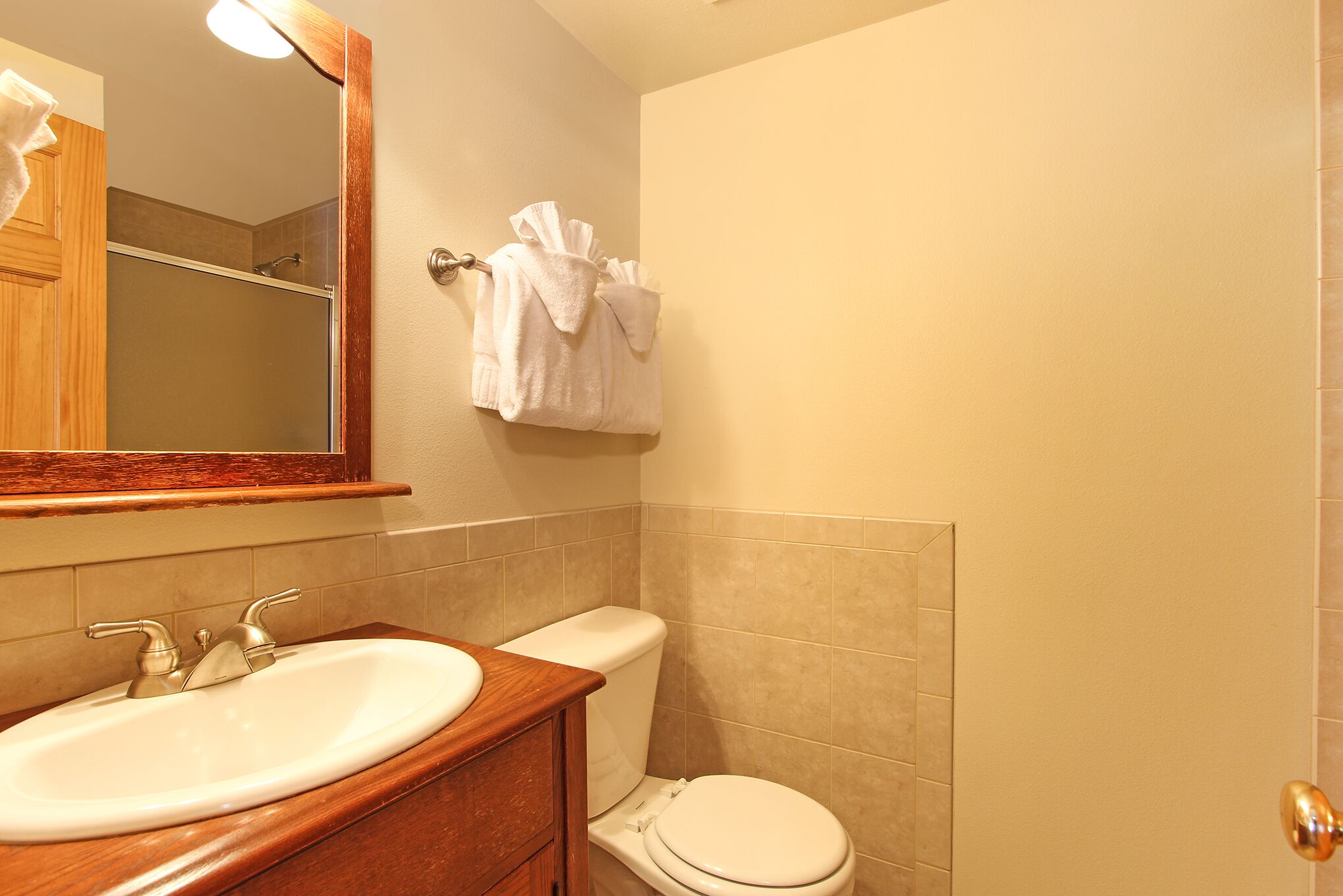A bathroom with a sink, mirror, toilet, and towel rack.