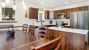 A modern kitchen with wooden cabinets, stainless steel appliances, and a dining area with a wooden table and chairs.
