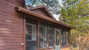 A rustic cabin with a stone foundation, large windows, and a number '630' on the side.