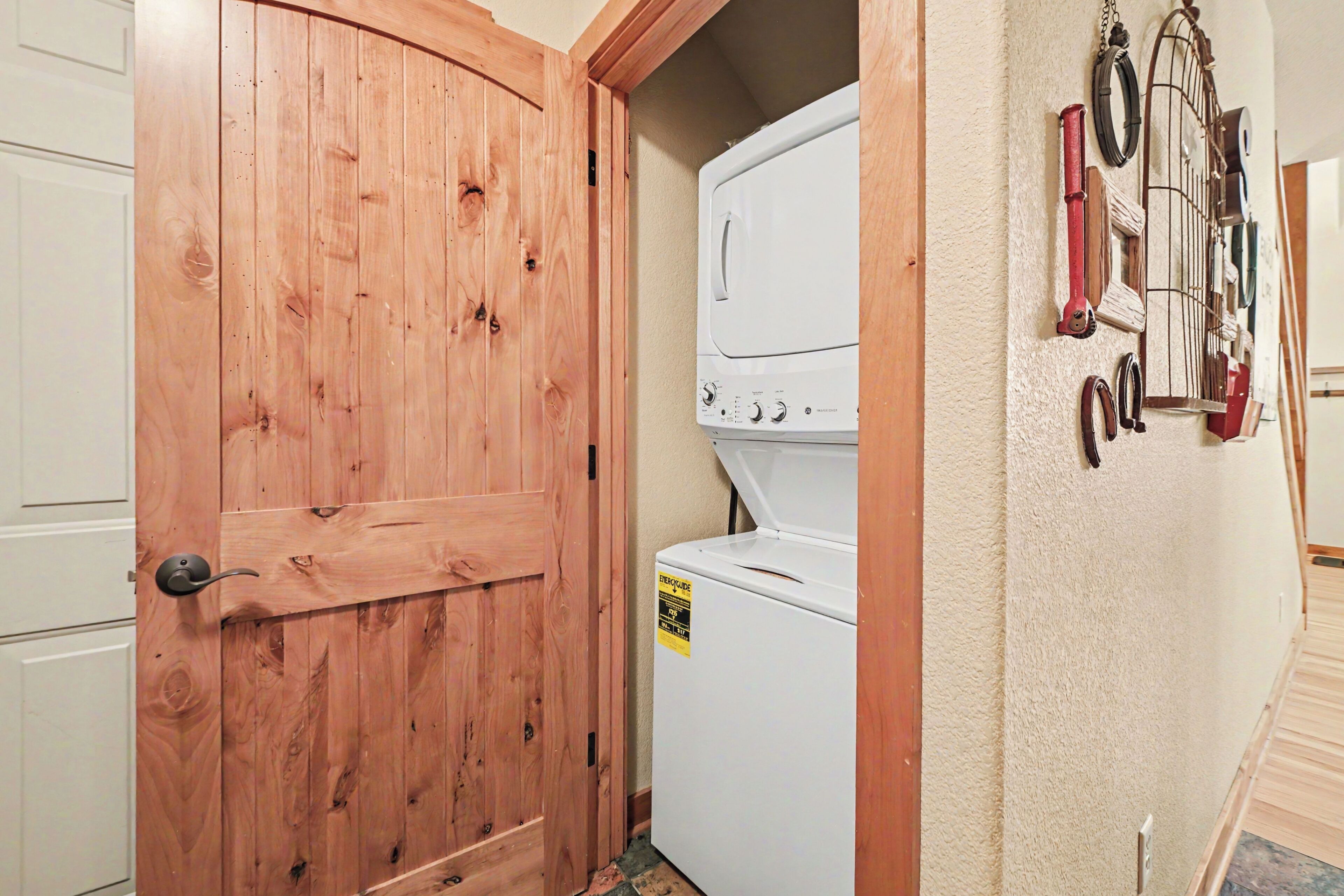 A laundry room with a wooden door, a white washing machine, and a towel rack with various items.