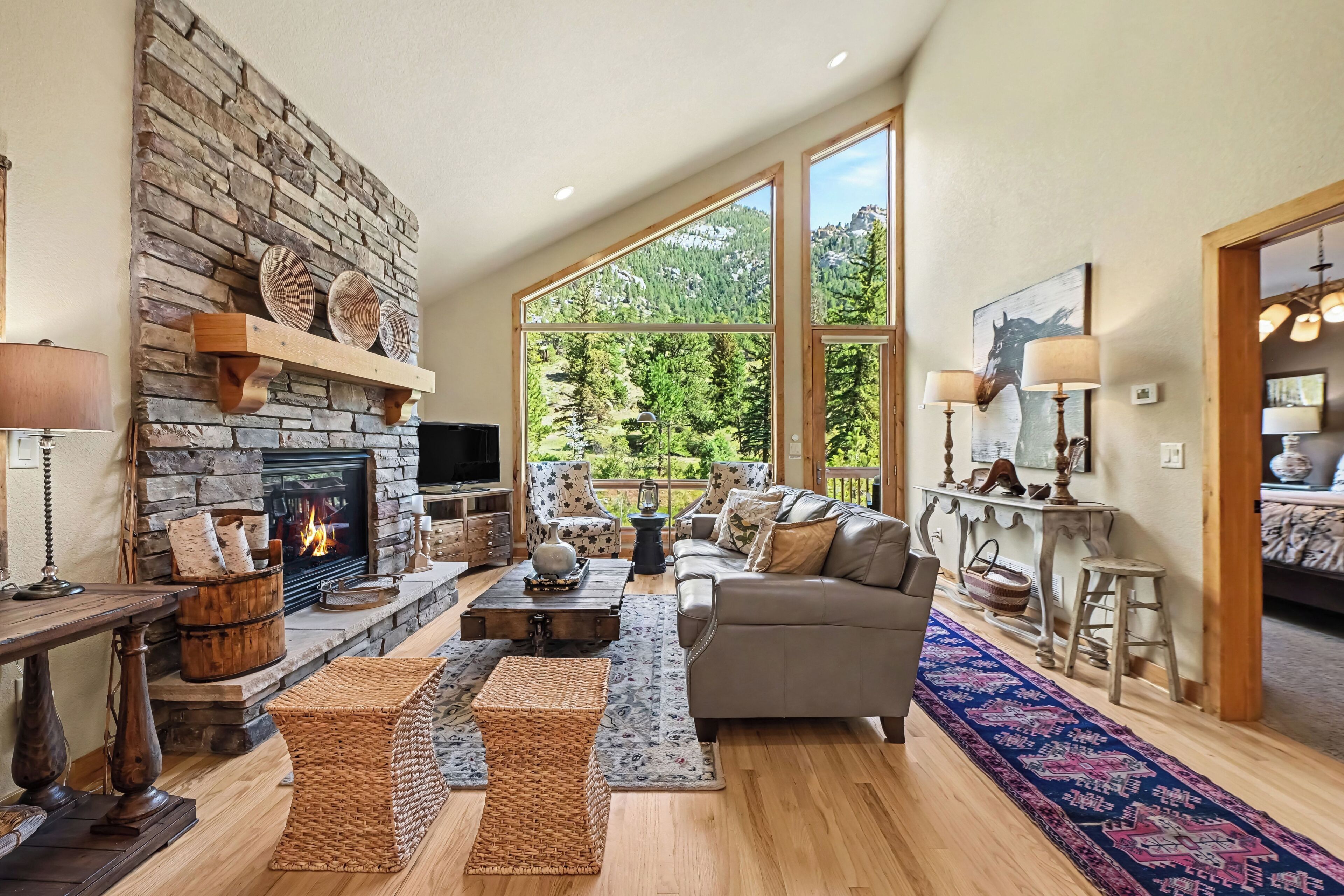 A spacious living room with a stone fireplace, large windows, and a cozy seating area.